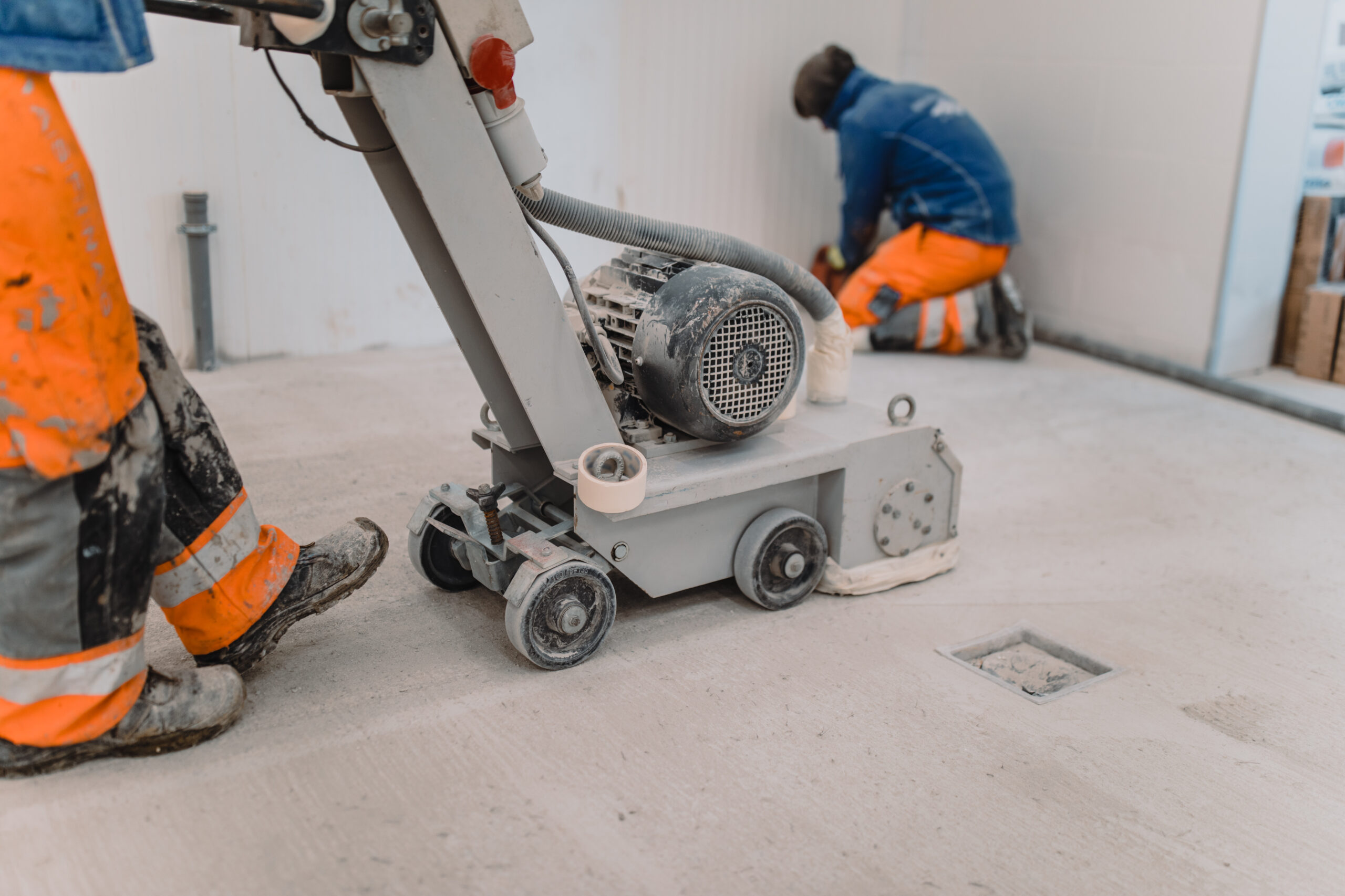 Workers grind the concrete floor at the construction site. seal warehouse floor