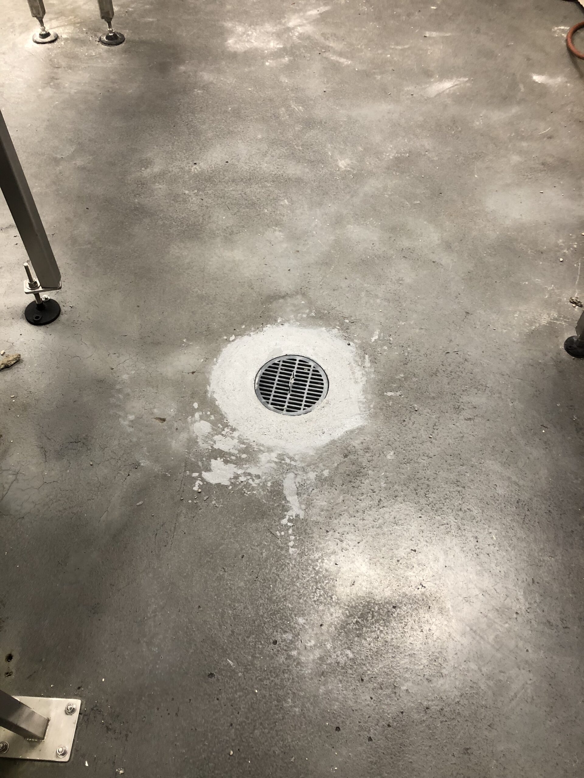 Concrete floor with a repaired drain area after resurfacing. — warehouse floor resurfacing when needed