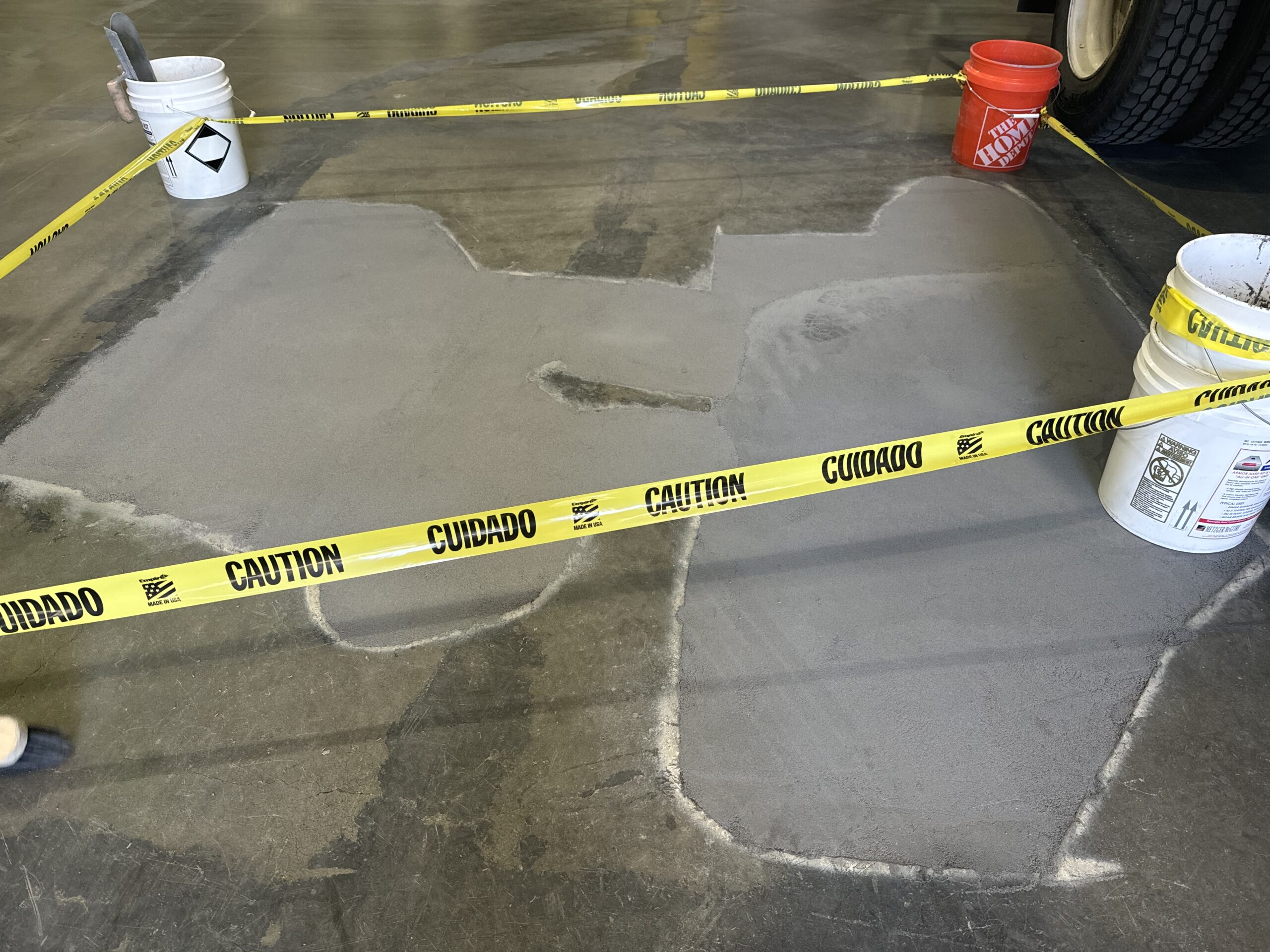 Concrete repair area marked off with caution tape and buckets.