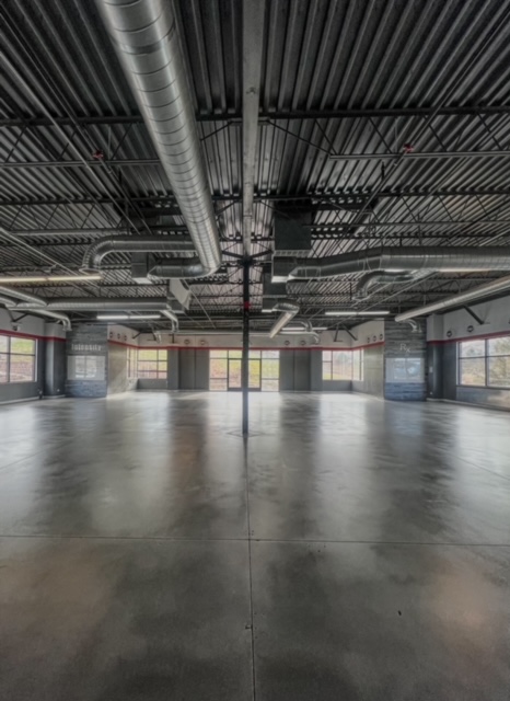 A spacious interior with polished concrete flooring and industrial ceiling. — polished concrete vs epoxy flooring