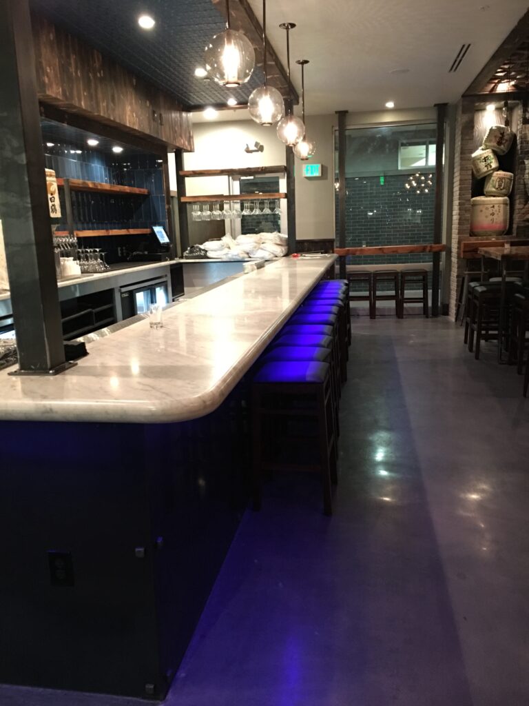 Polished concrete bar area with seating and ambient lighting.