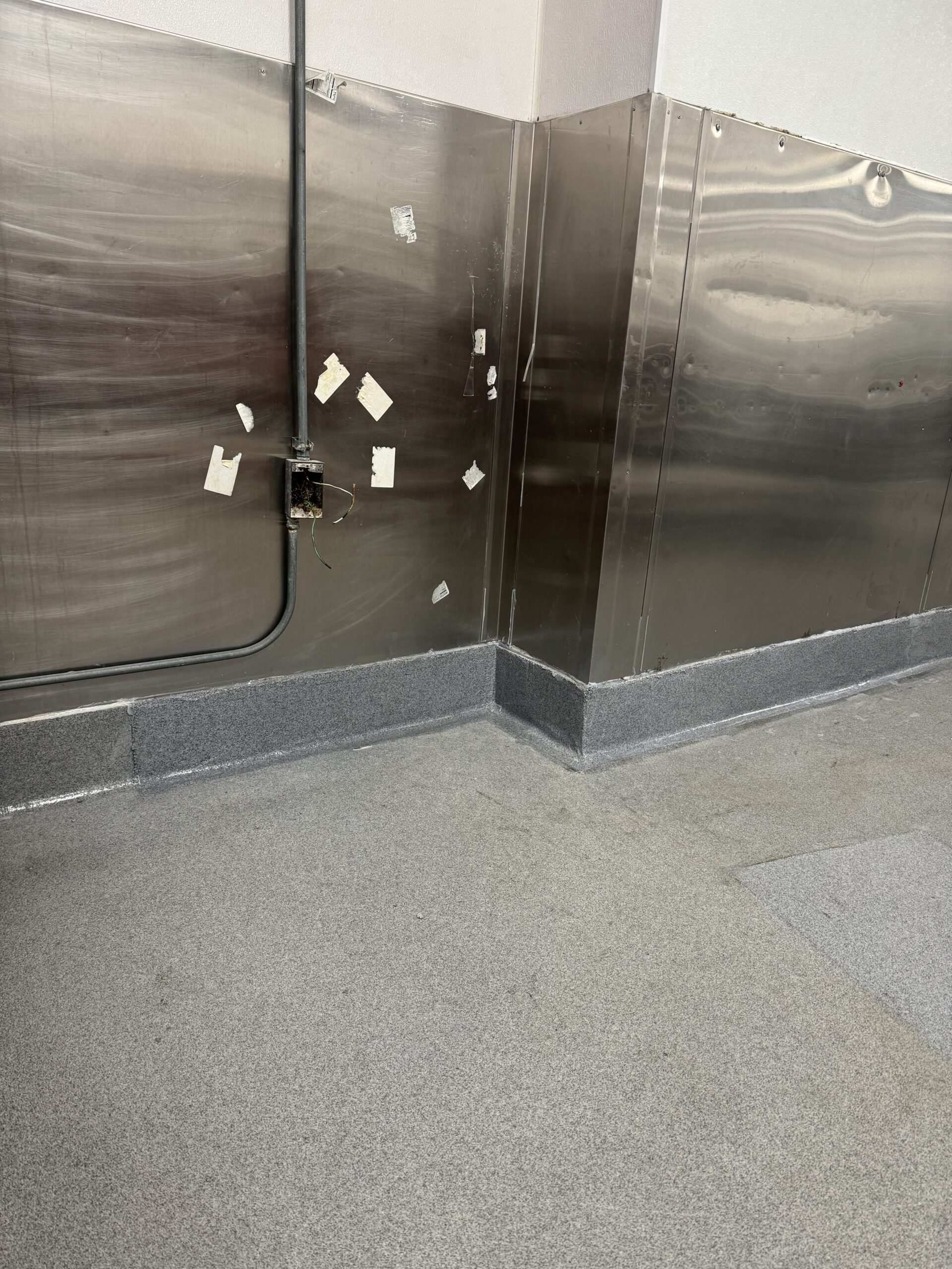 Close-up of a cove base and quartz broadcast epoxy flooring installation. — commercial cove base epoxy flooring