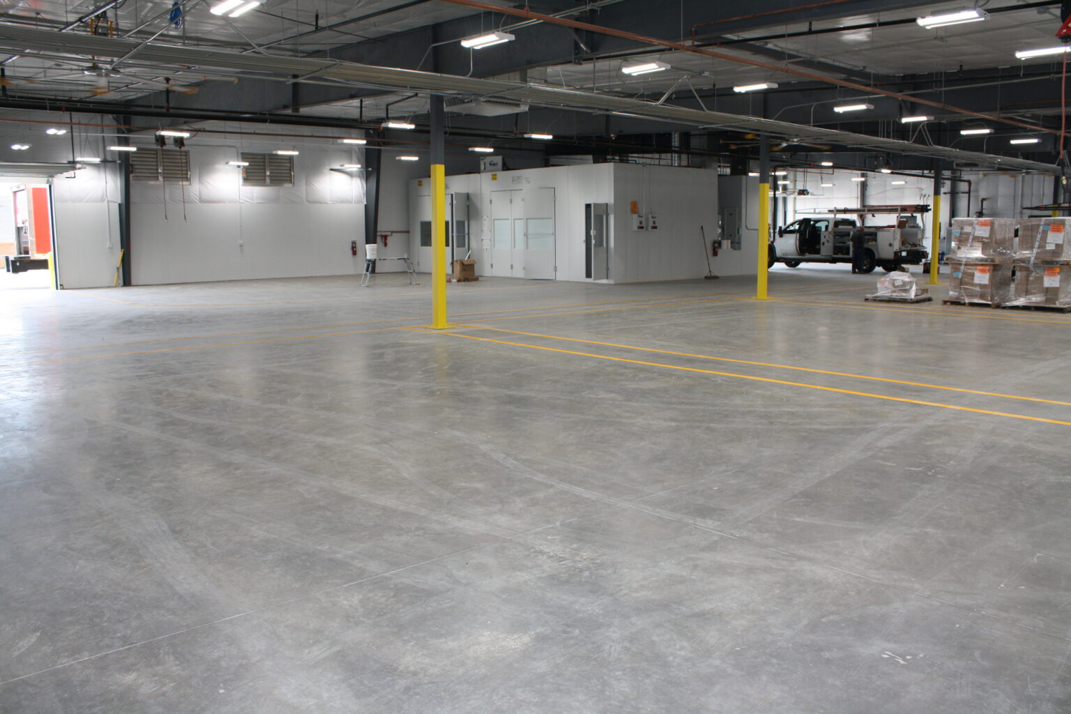 A polished concrete floor in a warehouse with yellow line striping
