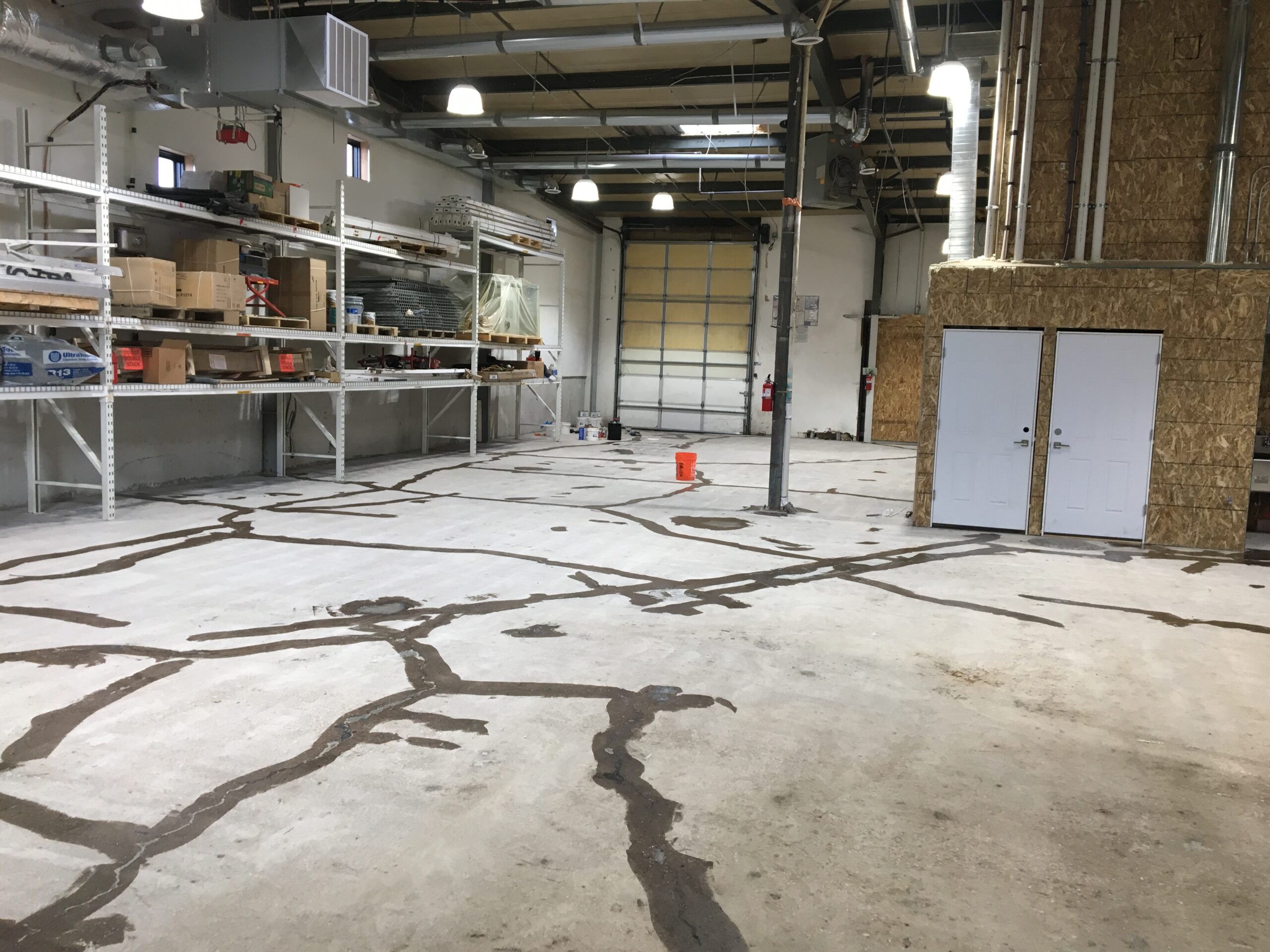 Wide shot of a workshop area showing the epoxy floor before surface preparation repairs.