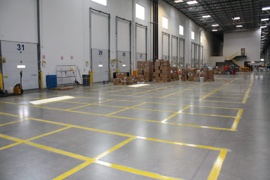 A warehouse interior with yellow line striping and stacked boxes.